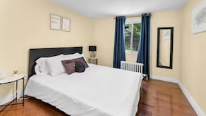 A neatly arranged hotel room with a bed, a small table, a lamp, and a window with curtains. - Cozy Family Retreat Minutes From Falls  (Niagara Falls)