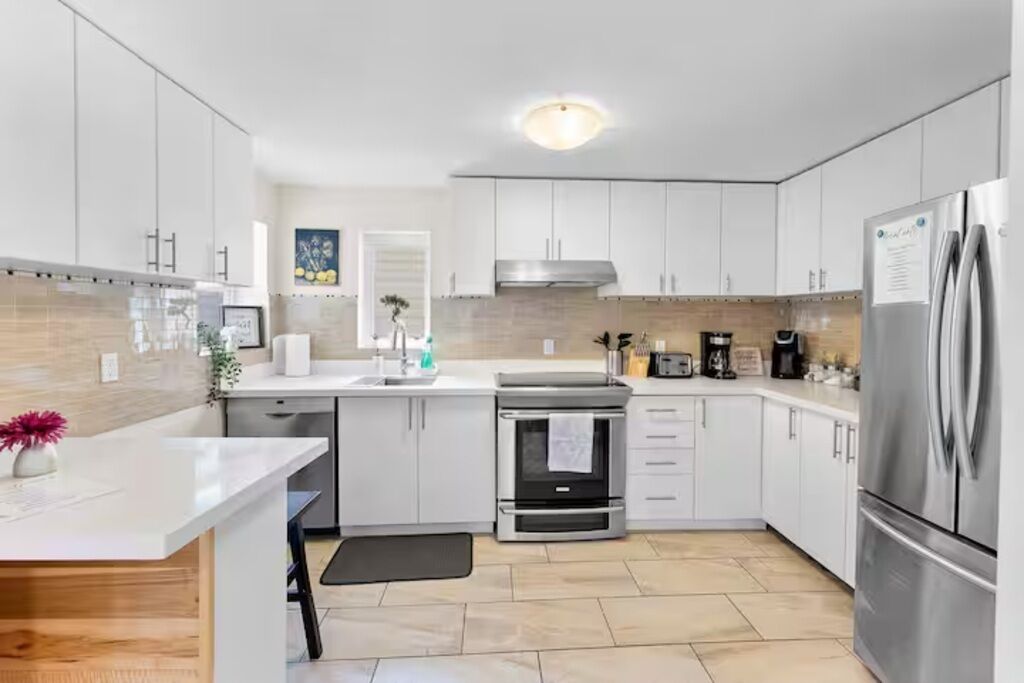 A modern kitchen with white cabinetry, stainless steel appliances, and a tiled backsplash.