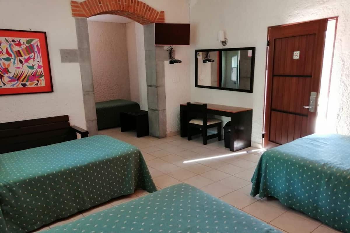 Une chambre avec deux lits, un bureau, une chaise, une télévision et une porte.