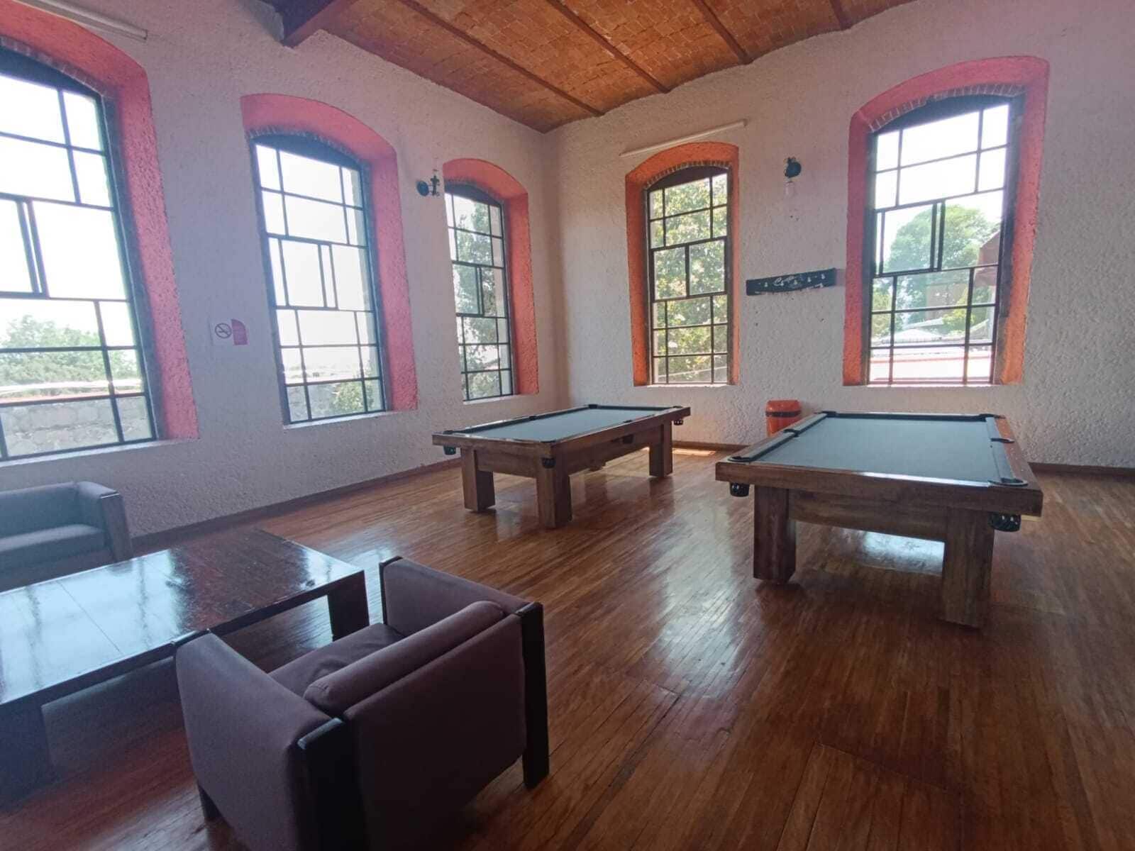 Een kamer met houten vloeren, twee pooltafels en een zithoek met een tafel en stoelen.