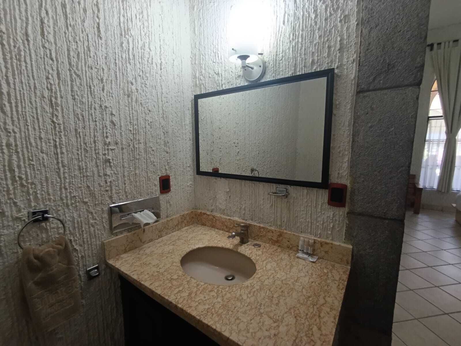 Un baño con lavamanos de mármol, un espejo y un perchero para toallas.