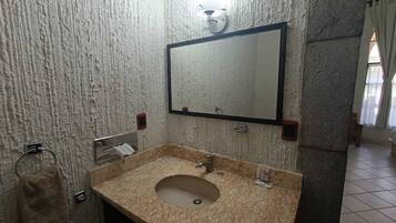 Un baño con lavamanos de mármol, un espejo y un perchero para toallas.