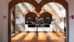 An interior with stone arches, a reception desk, and wooden flooring. - Centro Vacacional La Trinidad (Santa Cruz Tlaxcala)