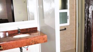 Une salle de bain équipée d’un lavabo, d’un miroir et d’une cabine de douche.
