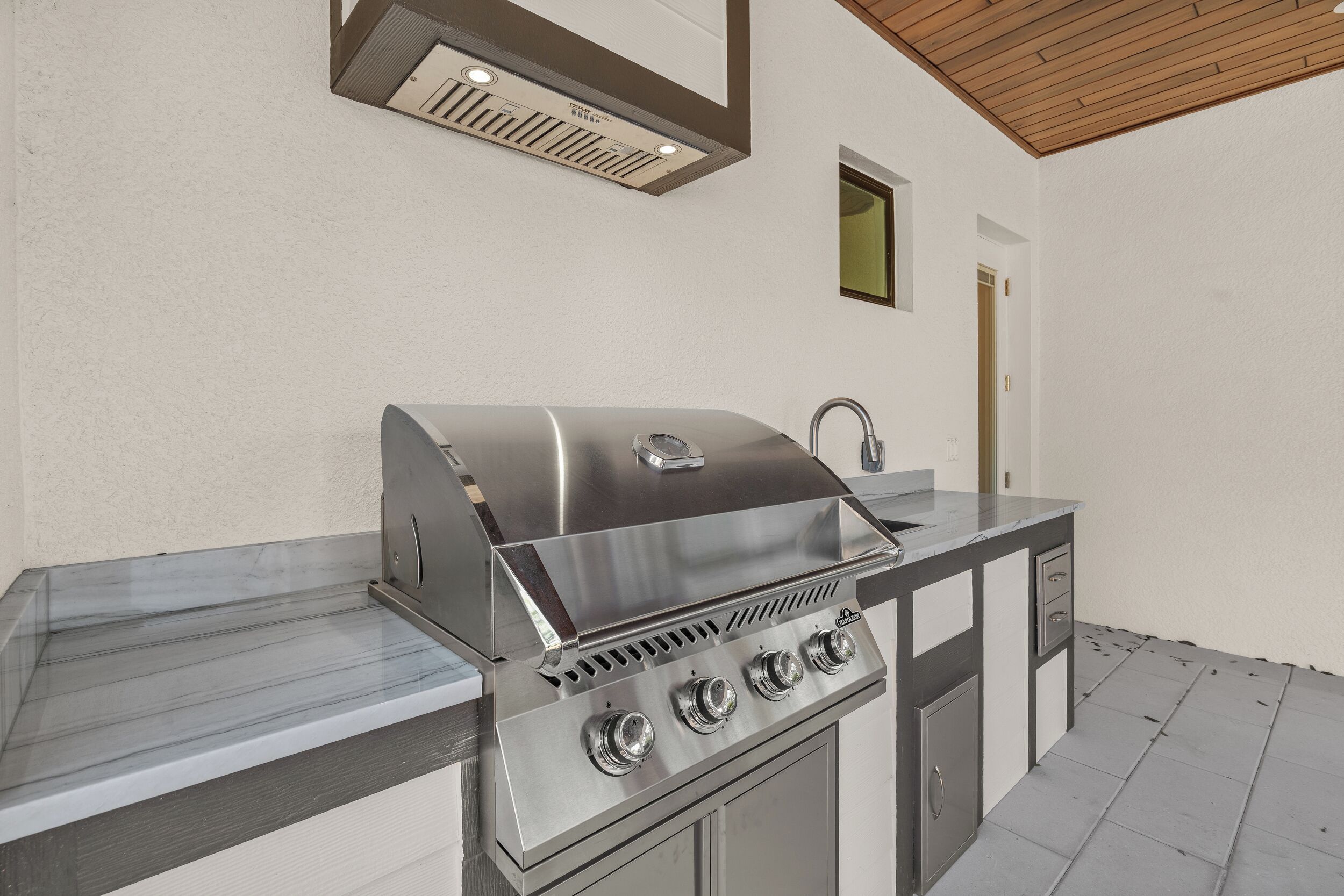Eine Outdoor-Küche aus Edelstahl mit integriertem Grill, einer Spüle und einem Schrank.