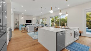 Una cocina moderna con una isla central, muebles blancos y electrodomésticos de acero inoxidable.