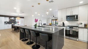 A modern kitchen with a central island, bar stools, stainless steel appliances, and pendant lighting. - Modern, spacious 6 BR/4 Bath house close to Old Town Scottsdale with Heated Pool (Scottsdale)