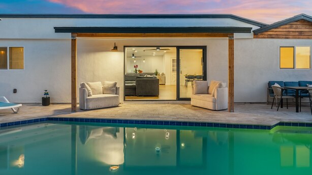A modern house with a swimming pool, a covered patio, and a kitchen visible through glass doors. - Modern, spacious 6 BR/4 Bath house close to Old Town Scottsdale with Heated Pool (Scottsdale)