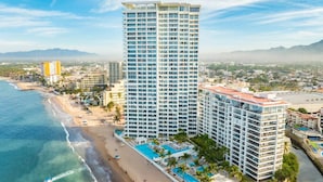 Ein Hochhaus-Hotel mit mehreren Balkonen, einer Strandlage und einem Poolbereich.