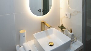 Un bagno moderno con un ampio specchio ovale, un lavandino bianco e un porta asciugamani con un asciugamano etichettato 'Make up'.
