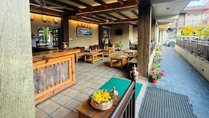 Hall d'albergo con arredi in legno, una reception e vista sulla strada.