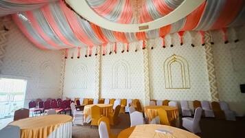 A banquet hall with round tables, chairs, and a patterned wall.