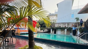 Area piscina con una palma, un ombrellone rosso e un cartello che indica la zona spa.