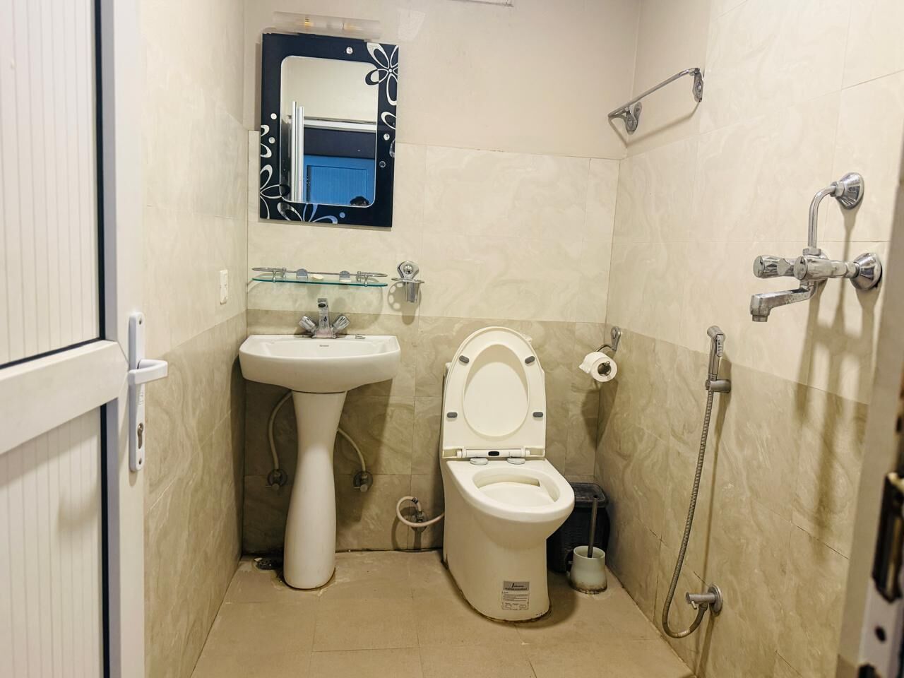 A small bathroom with a pedestal sink, toilet, and shower.