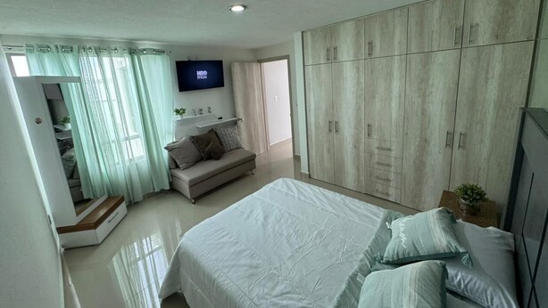 Un dormitorio con cama, sofá, televisor y armario.