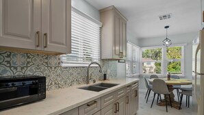 A modern kitchen with a built-in oven, a double sink, and a dining area with a table and chairs. - Boho 3BR Alhambra, Sleeps 8, Pet OK, DTLA/Disney/Universal/World Cup/Olympics (Alhambra)
