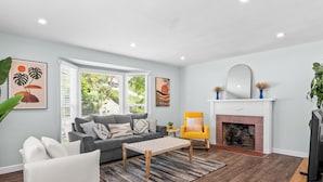 A modern living room with a grey sofa, white armchair, and a yellow armchair. There is a fireplace, a television, and artwork on the walls. - Boho 3BR Alhambra, Sleeps 8, Pet OK, DTLA/Disney/Universal/World Cup/Olympics (Alhambra)