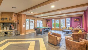 A spacious indoor area with a pool table, comfortable seating, and a stone fireplace. - Appartement Rocca - Welkeys (Saint-Gervais-les-Bains)