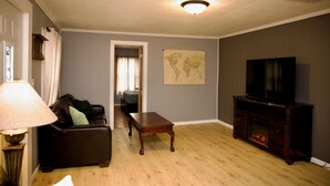 Ein Wohnzimmer mit einer Couch, einem Couchtisch, einem Kamin und einem Fernseher.