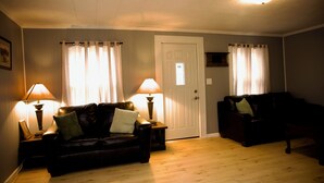 Ein Wohnzimmer mit zwei Sofas, einer Tür und zwei Lampen.