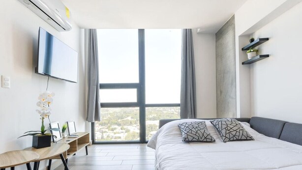 Een moderne slaapkamer met een groot bed, een bureau en een televisie aan de muur.