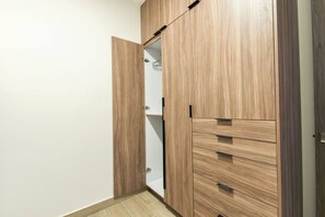 A wooden wardrobe with multiple drawers and a hanging space. - ¡Cerca de Fundidora! 4 camas, alberca & Gym 6H (Monterrey)