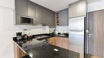A modern kitchen with a black granite countertop, stainless steel appliances, and wooden cabinets.