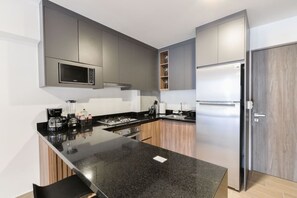 Une cuisine moderne dotée d’un plan de travail en granit noir, d’appareils électroménagers en acier inoxydable et d’armoires en bois.