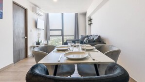 Een eetruimte met een tafel voor vier personen, een bank en een groot raam met uitzicht.