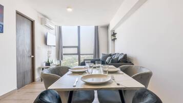 A dining area with a table set for four, a sofa, and a large window offering a view.
