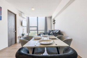Un comedor con una mesa preparada para cuatro, un sofá y un amplio ventanal con vistas.