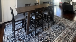 A dining area with a wooden table and chairs, a patterned rug, and a painting on the wall. - Fantastic 3-bedroom house with AC in friendly Wichita neighborhood (Wichita)