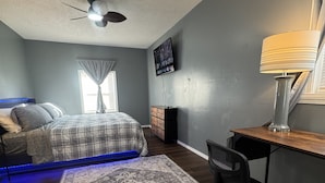 A bedroom with a bed, a desk, a chair, a TV, a ceiling fan, and a window with curtains. - Fantastic 3-bedroom house with AC in friendly Wichita neighborhood (Wichita)