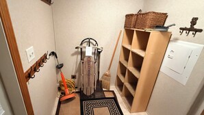 A compact utility room with a broom, mop, and a wall-mounted rack with hooks. - Charming 3 Bed Room Monthly Rental in the Heart of Ellicottville (Ellicottville)