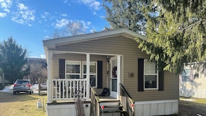 A small, single-story mobile home with a porch and a front door. - Charming 3 Bed Room Monthly Rental in the Heart of Ellicottville (Ellicottville)