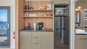 A modern kitchen with wooden accents, a stainless steel refrigerator, and a microwave. - Waterfront A-Frame Panoramic Sunset Views (Fort Walton Beach)