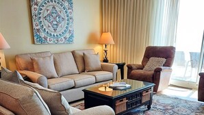 Una sala de estar con un sofá, sillones, una mesita de centro y un tapete estampado.