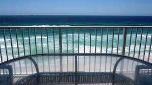 Un balcone con vista sull'oceano, dotato di ringhiera in vetro e sedie in vimini.