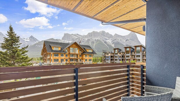 Ein Holzhaus mit mehreren Balkonen, einem Holzzaun und Blick auf die Berge.