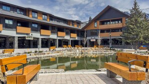 Ein modernes Gebäude mit einem Innenhof, der einen Teich und Holzbanken beinhaltet.