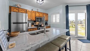 Una cocina moderna con armarios de madera, electrodomésticos de acero inoxidable, encimera de mármol y vistas al exterior.