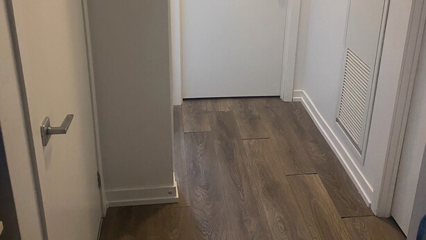 A hallway with a wooden floor, white walls, and a closed door. - 2 bedroom 2 bathroom condominium downtown Toronto (Toronto)
