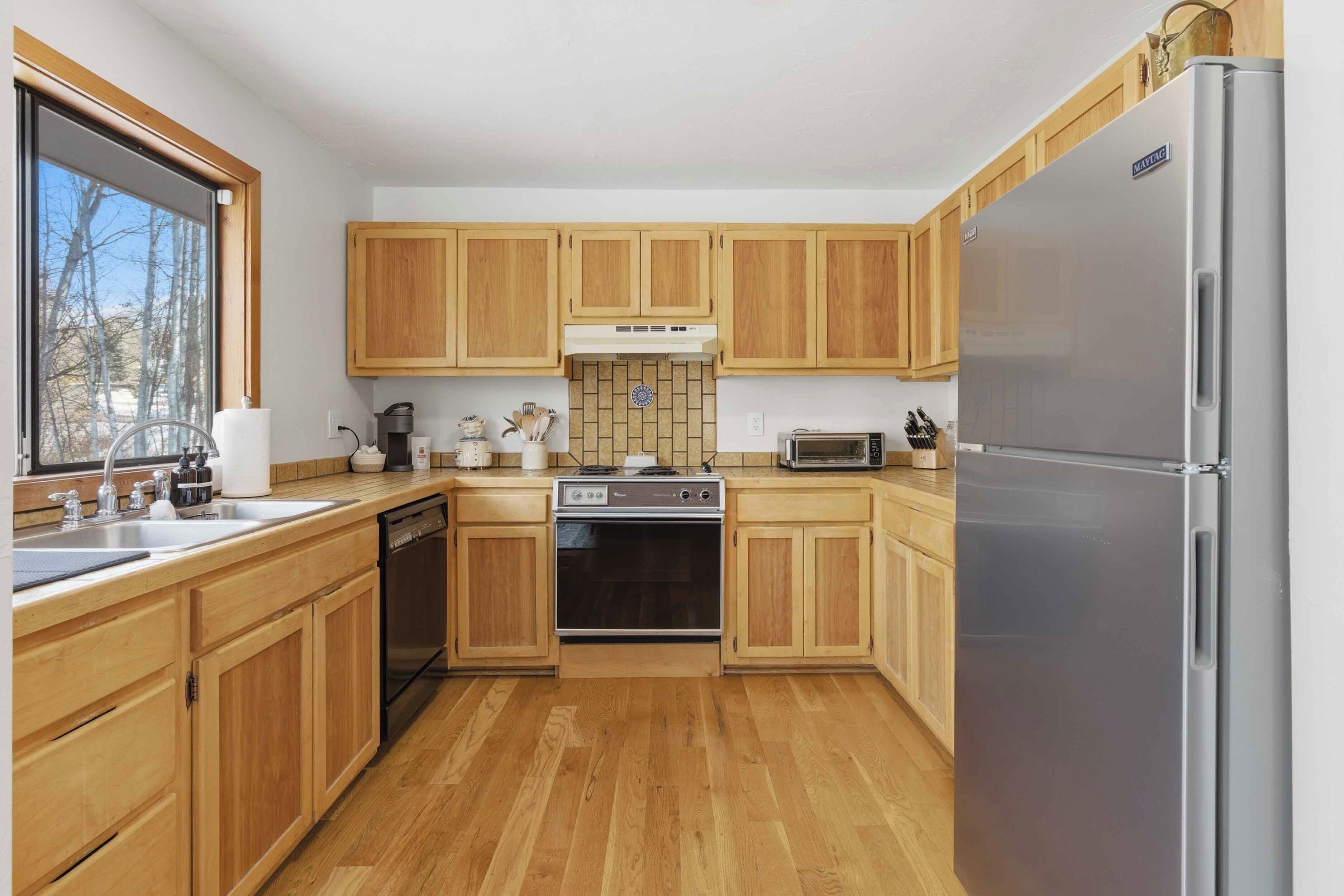 A kitchen with wooden cabinets, a stainless steel refrigerator, a built-in oven, and a microwave.