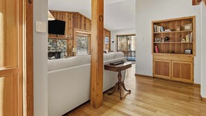 A spacious living room with a white sofa, wooden accents, a stone fireplace, and a bookshelf. - The Aspen Hideaway | Elkhorn Pool, Hot Tub + Pickleball (Sun Valley)