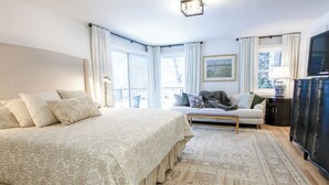 A bedroom with a large bed, a sofa, a dresser, and a window with curtains. - Spacious 5-bedroom house in gorgeous, convenient Avon with pool and fitness room (Avon)