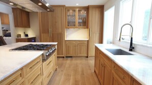 A modern kitchen with wooden cabinets, a stainless steel stove, and a large window. - Spacious 5-bedroom house in gorgeous, convenient Avon with pool and fitness room (Avon)