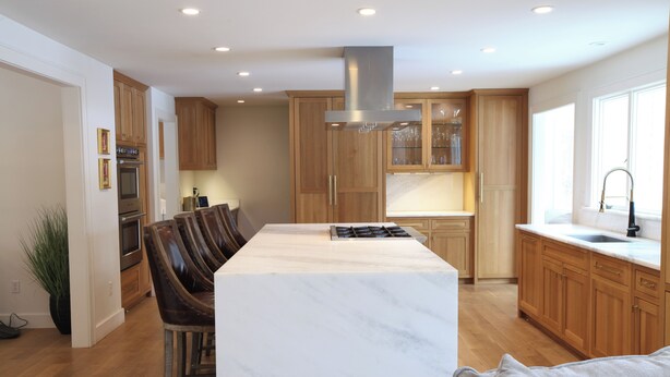 A modern kitchen with wooden cabinets, a marble island, and a built-in stove. - Spacious 5-bedroom house in gorgeous, convenient Avon with pool and fitness room (Avon)