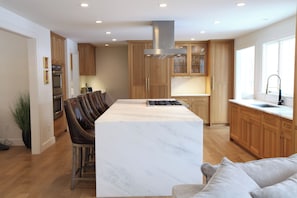 A modern kitchen with wooden cabinets, a marble island, and a built-in stove. - Spacious 5-bedroom house in gorgeous, convenient Avon with pool and fitness room (Avon)