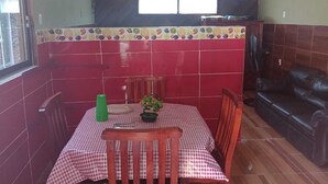 A dining area with a checkered tablecloth, wooden chairs, a green bottle, and a potted plant. - Estancia La Quinta María 2 (Veracruz)