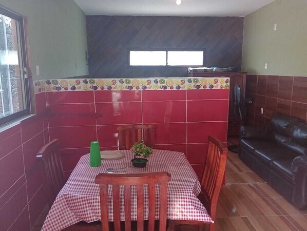 Un comedor con mantel a cuadros, sillas de madera, una botella verde y una planta en maceta.